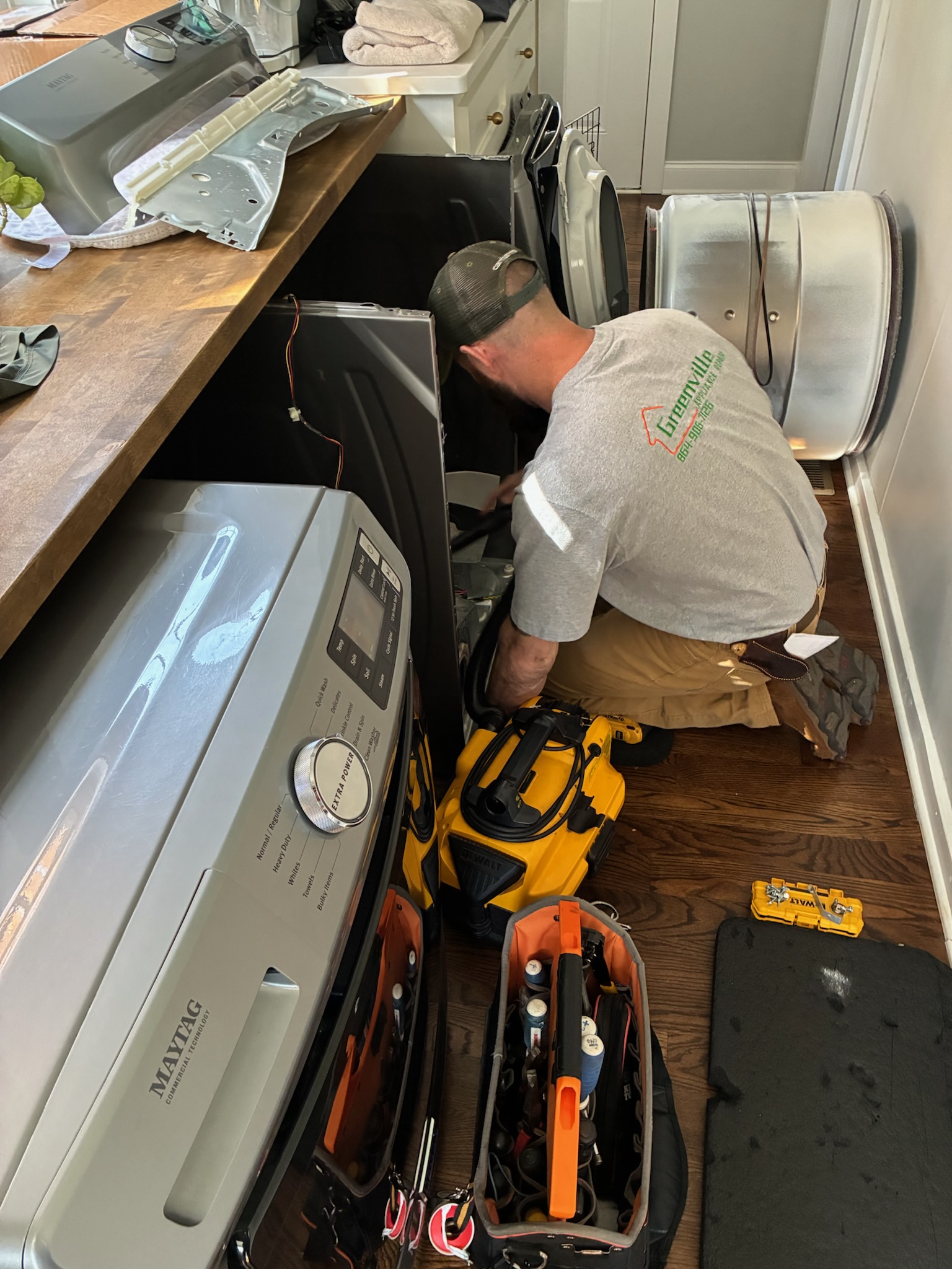Blake Miller repairing a Maytag washer in a customer's laundry room